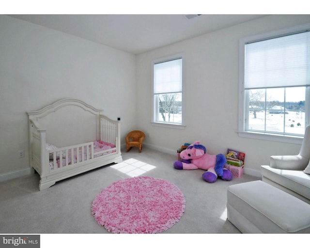 bedroom featuring light carpet and a nursery area