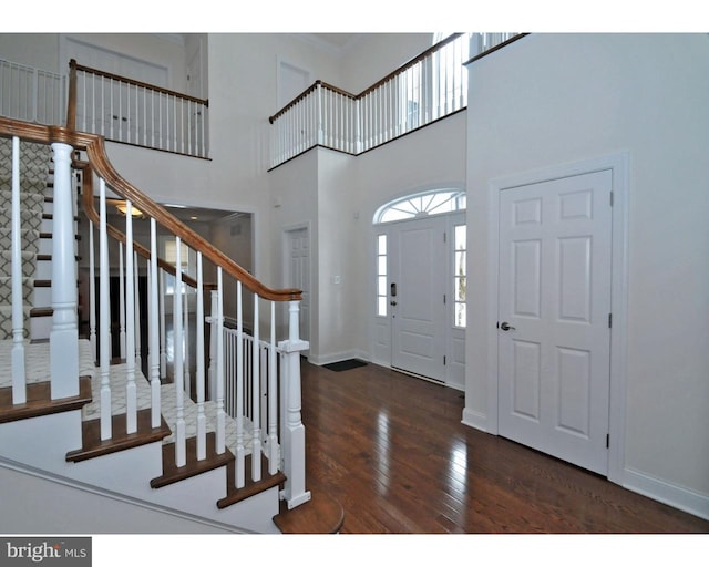 entrance foyer with a towering ceiling and dark hardwood / wood-style floors