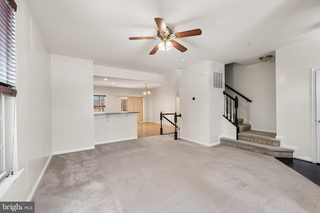 unfurnished living room featuring carpet flooring and ceiling fan with notable chandelier