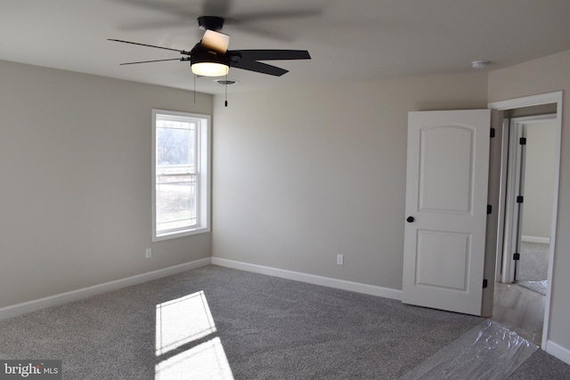 empty room with ceiling fan and dark carpet