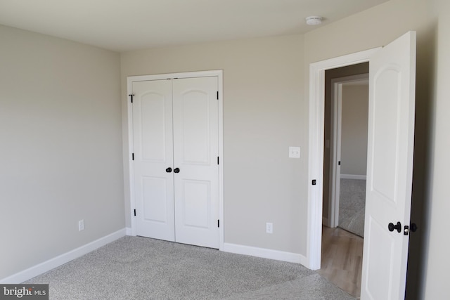 unfurnished bedroom with a closet and light colored carpet