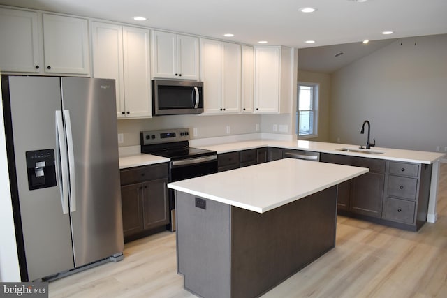 kitchen featuring white cabinets, sink, appliances with stainless steel finishes, a kitchen island, and kitchen peninsula