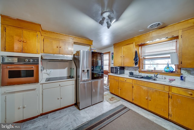 kitchen featuring black appliances, backsplash, a healthy amount of sunlight, and sink