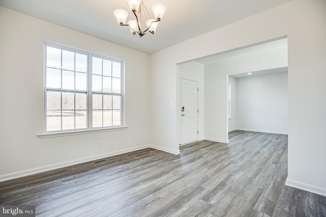 unfurnished room featuring a chandelier and wood-type flooring