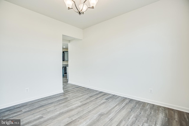 empty room featuring light wood-type flooring and an inviting chandelier