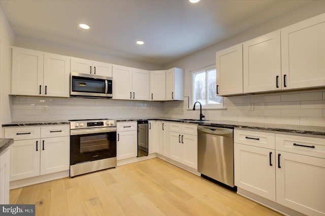 kitchen featuring tasteful backsplash, sink, stainless steel appliances, and light wood-type flooring