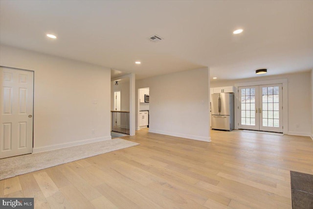 unfurnished living room with french doors and light wood-type flooring