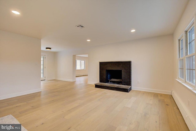 unfurnished living room featuring a fireplace, a baseboard radiator, and light wood-type flooring