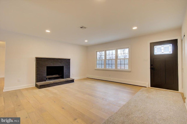 unfurnished living room with a fireplace, light hardwood / wood-style floors, and baseboard heating