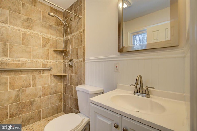 bathroom featuring a tile shower, vanity, and toilet