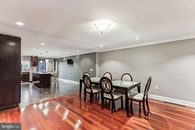 dining space featuring dark hardwood / wood-style floors and crown molding