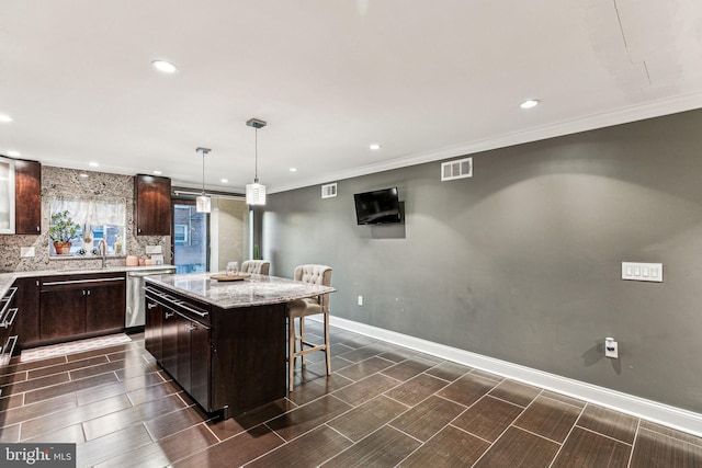 kitchen featuring dark brown cabinetry, a center island, light stone counters, pendant lighting, and a kitchen bar