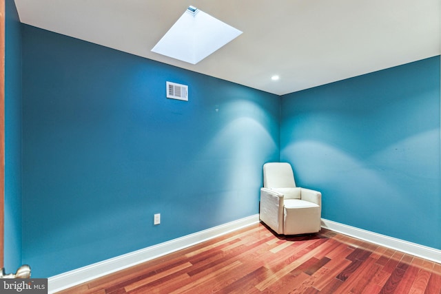 unfurnished room featuring wood-type flooring and a skylight