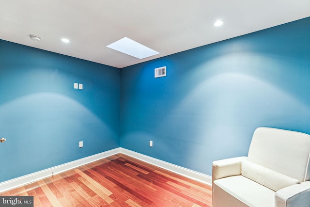 sitting room with hardwood / wood-style flooring and a skylight