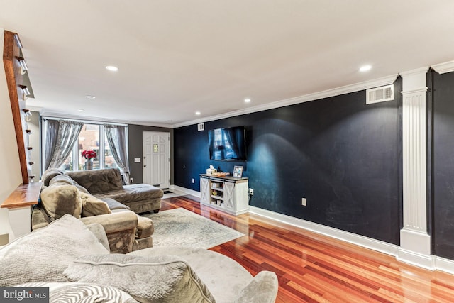 living room featuring hardwood / wood-style flooring, decorative columns, and crown molding