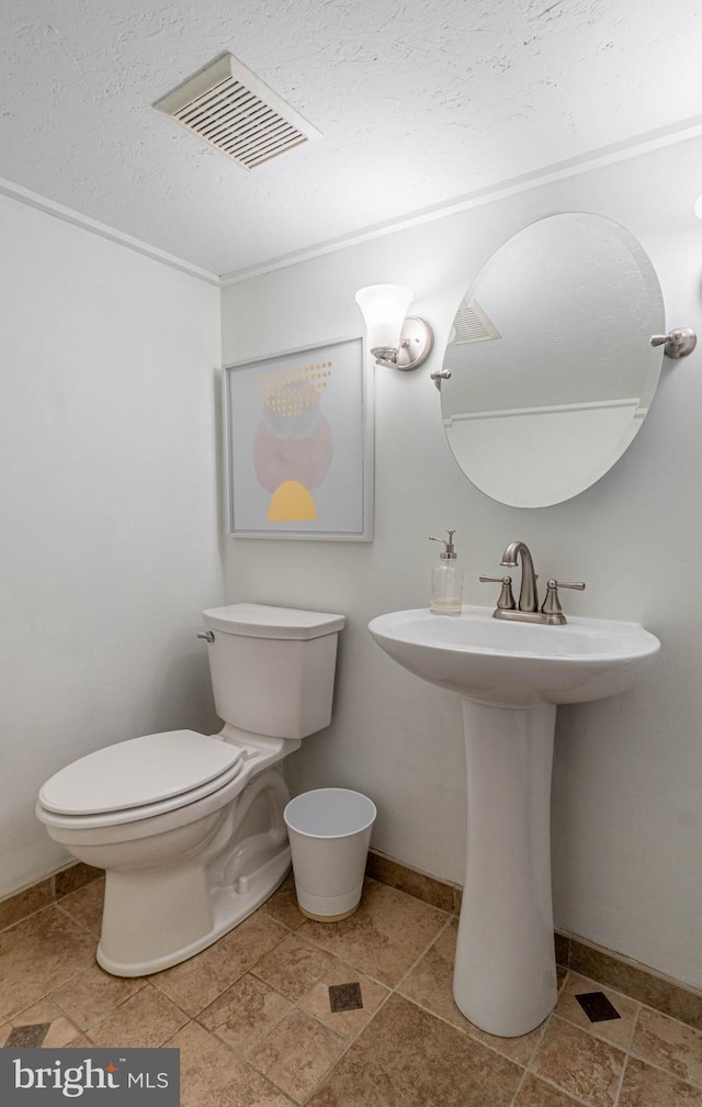 bathroom with a textured ceiling, toilet, and sink