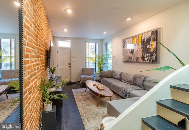 living room featuring dark hardwood / wood-style floors, a healthy amount of sunlight, and brick wall