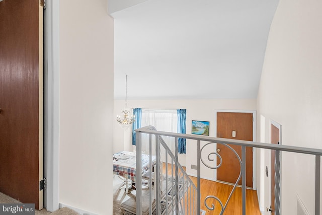 staircase with wood-type flooring, vaulted ceiling, and a notable chandelier