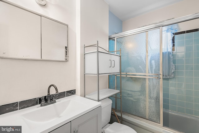 full bathroom with bath / shower combo with glass door, vanity, and toilet