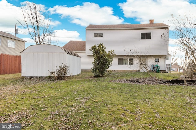 rear view of property with a yard and a storage unit