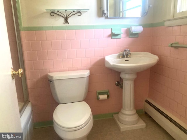 bathroom with toilet, tile walls, and a baseboard radiator