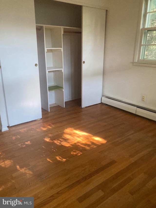 interior space featuring dark hardwood / wood-style flooring, baseboard heating, and a closet