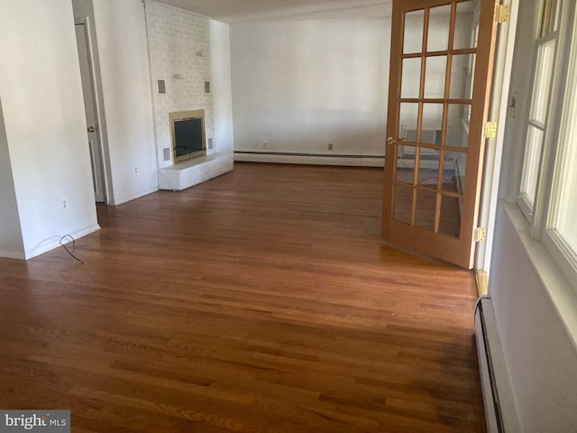 unfurnished living room with baseboard heating, dark hardwood / wood-style flooring, and a fireplace