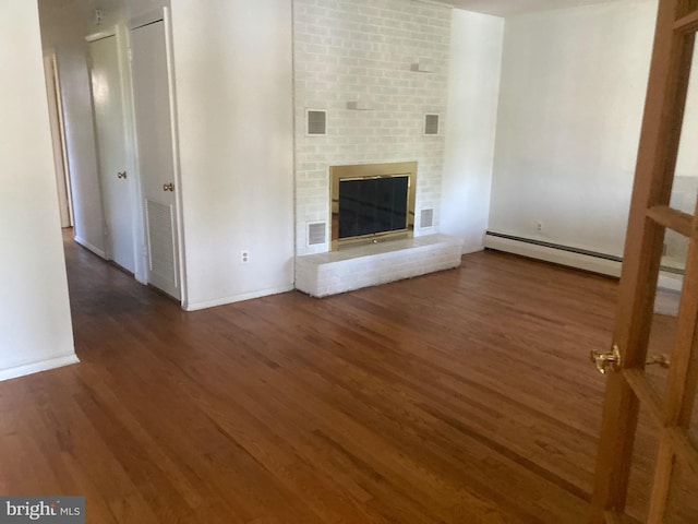 unfurnished living room featuring a fireplace, dark hardwood / wood-style flooring, and a baseboard heating unit