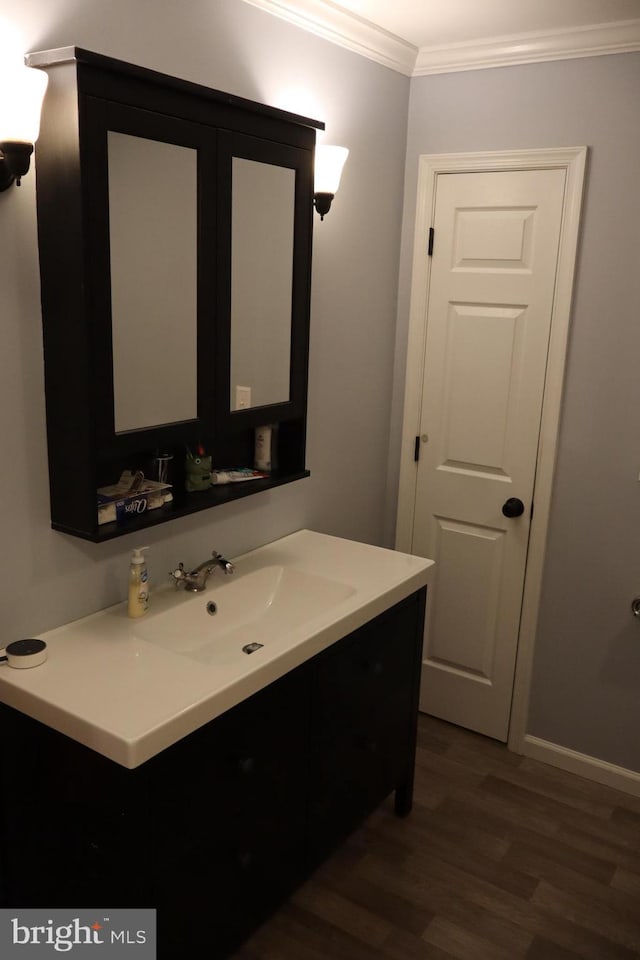 bathroom featuring crown molding, hardwood / wood-style flooring, and vanity