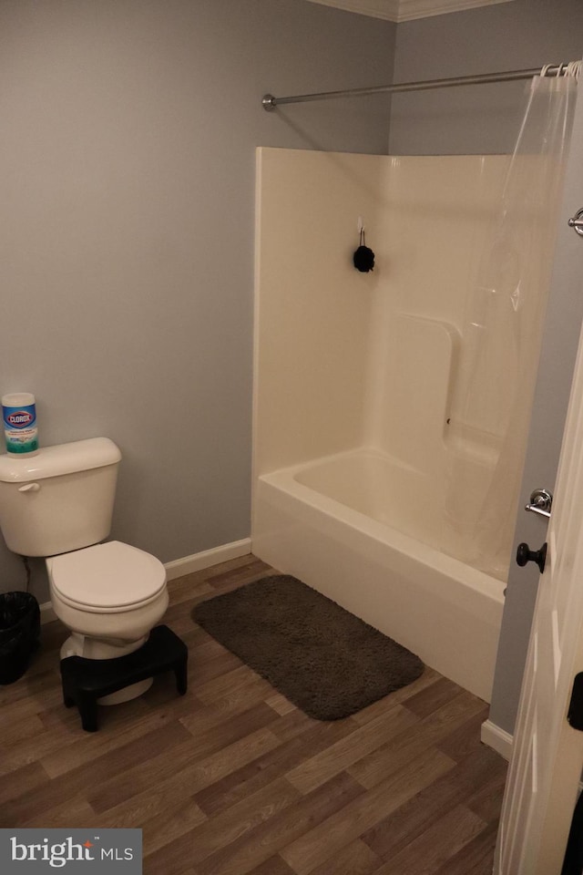 bathroom with hardwood / wood-style flooring, shower / bath combination, and toilet