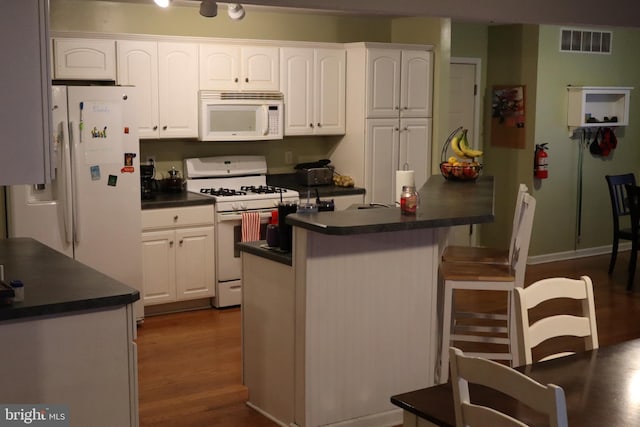 kitchen with white cabinetry, a center island, dark hardwood / wood-style floors, and white appliances