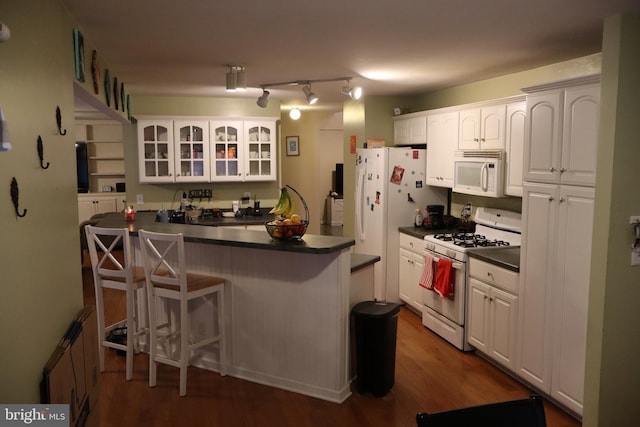 kitchen with kitchen peninsula, white appliances, and white cabinetry