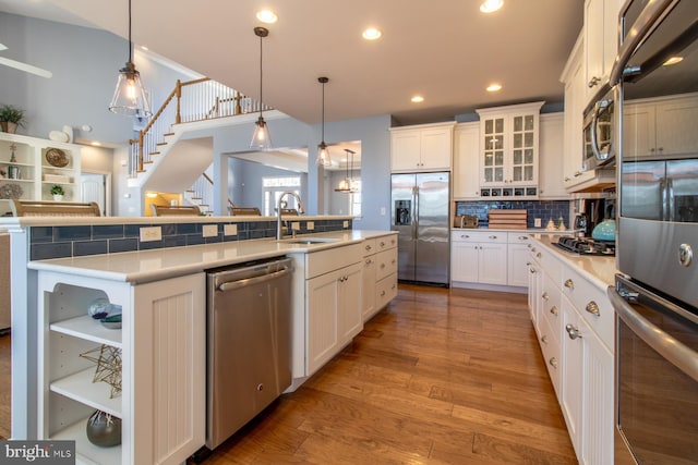 kitchen with a kitchen island with sink, white cabinets, decorative light fixtures, and appliances with stainless steel finishes