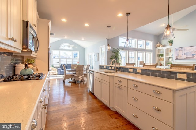 kitchen featuring lofted ceiling, white cabinets, sink, decorative backsplash, and appliances with stainless steel finishes