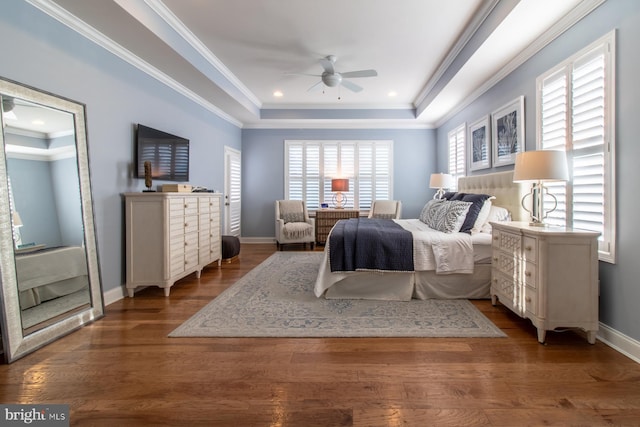 bedroom with ceiling fan, dark hardwood / wood-style floors, ornamental molding, and a tray ceiling