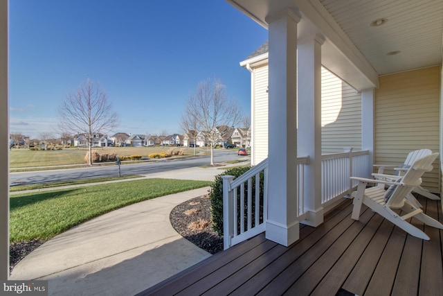 wooden terrace with a lawn and a porch