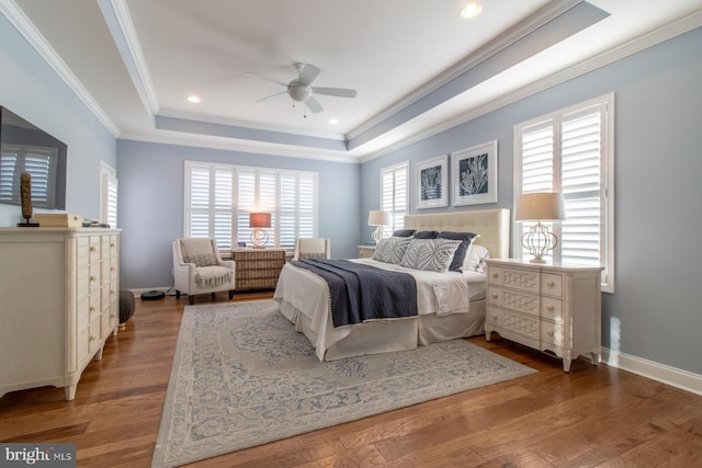 bedroom featuring ceiling fan, a raised ceiling, wood-type flooring, and crown molding