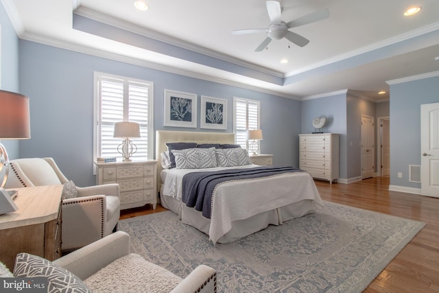 bedroom featuring hardwood / wood-style floors, a raised ceiling, ceiling fan, and crown molding