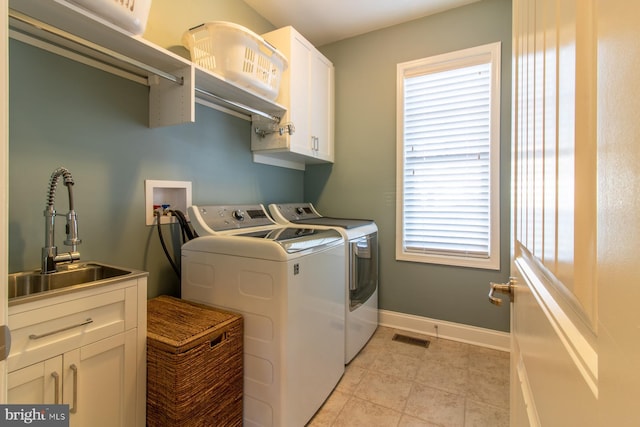 clothes washing area featuring sink, cabinets, and independent washer and dryer