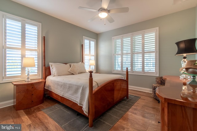 bedroom with multiple windows, ceiling fan, and dark hardwood / wood-style flooring