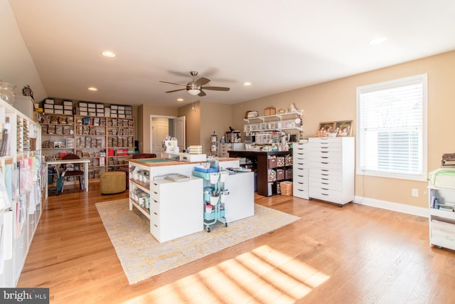 kitchen featuring ceiling fan, a kitchen island with sink, and light wood-type flooring