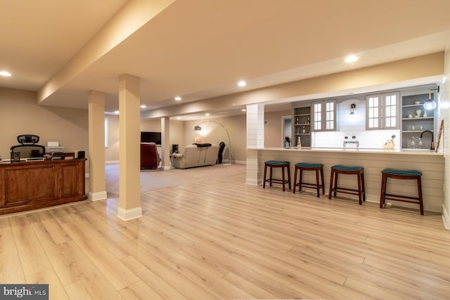 bar with light wood-type flooring, backsplash, and sink