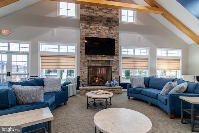 living room with a wealth of natural light, beamed ceiling, high vaulted ceiling, a fireplace, and carpet