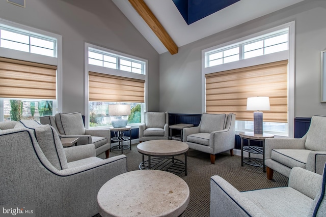 carpeted living room with beam ceiling and high vaulted ceiling