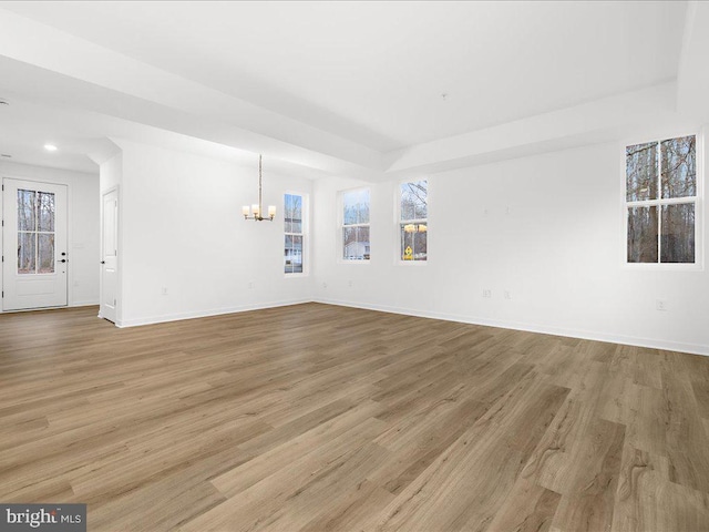 unfurnished living room with a notable chandelier and light hardwood / wood-style floors