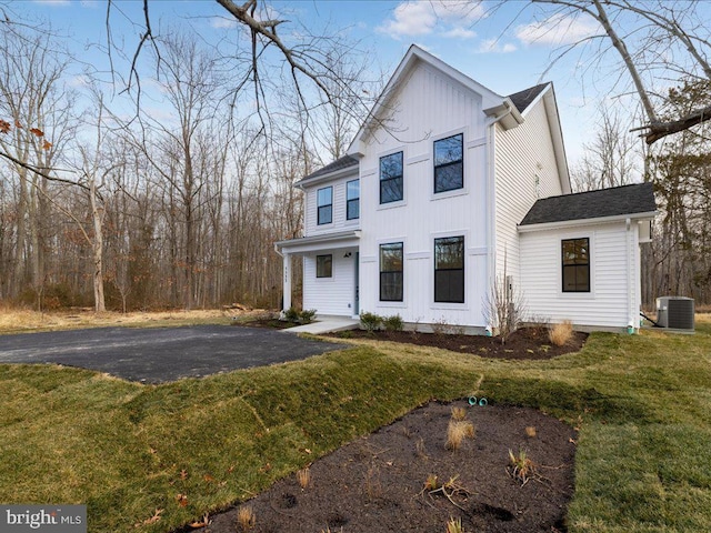 modern farmhouse with board and batten siding, a front yard, and central air condition unit