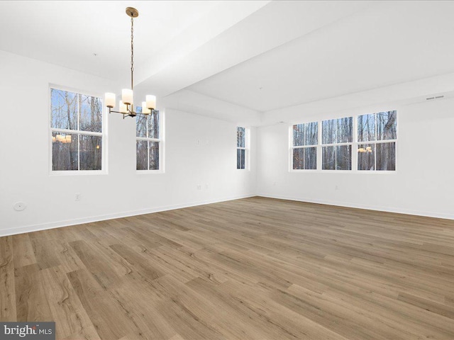 unfurnished room with hardwood / wood-style floors, a notable chandelier, and a raised ceiling