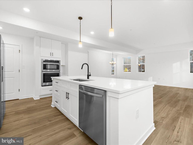 kitchen with pendant lighting, sink, an island with sink, white cabinetry, and stainless steel appliances