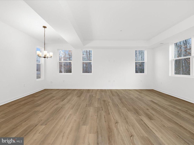 unfurnished living room featuring a tray ceiling, a notable chandelier, and hardwood / wood-style flooring