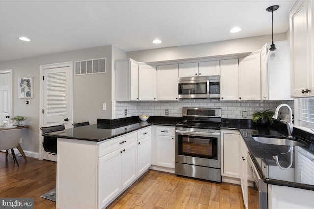 kitchen with white cabinetry, sink, kitchen peninsula, pendant lighting, and appliances with stainless steel finishes